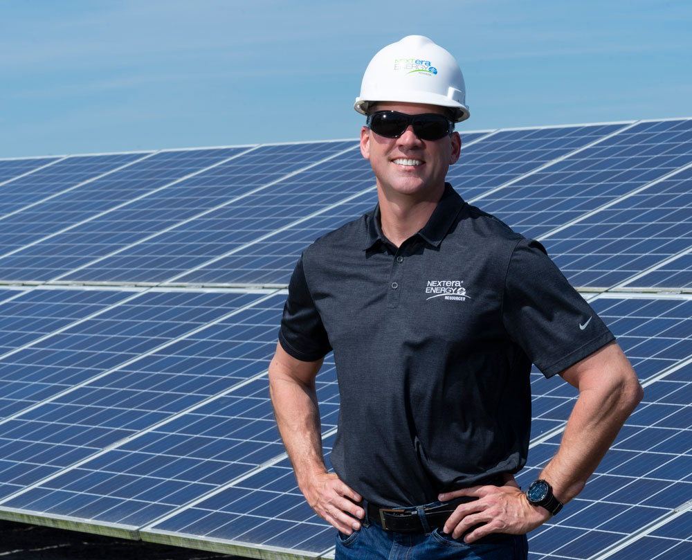 NextEra Energy Resources employee standing in front of a solar panel NextEra Energy Resources employee standing in front of a solar panel