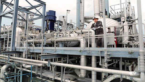 Construction worker using equipment while wearing a blue hard hat and yellow construction vest 