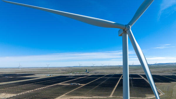 Close up of turbine with solar panels in the distance