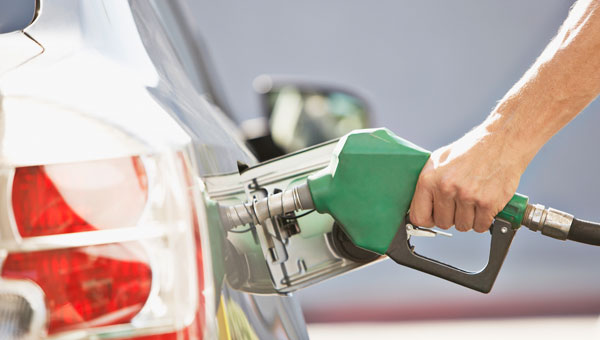 Hand placing gas pump into car fuel tank