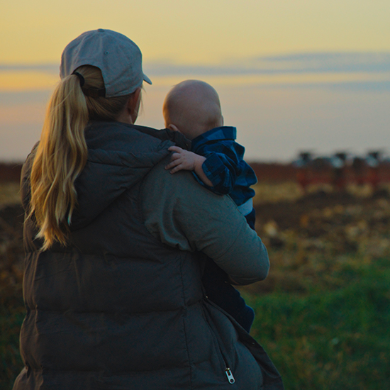 Landowner with her child looking at a tractor
