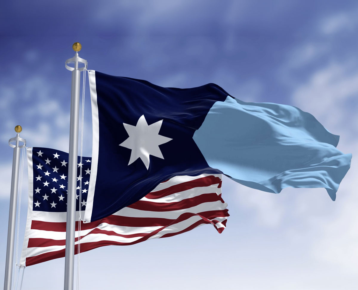 American flag and Minnesota state flag blowing in the wind against a blue sky