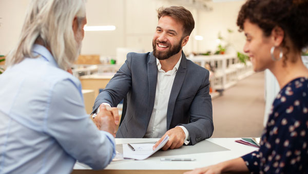 Professional handshake at office meeting with documents on desk