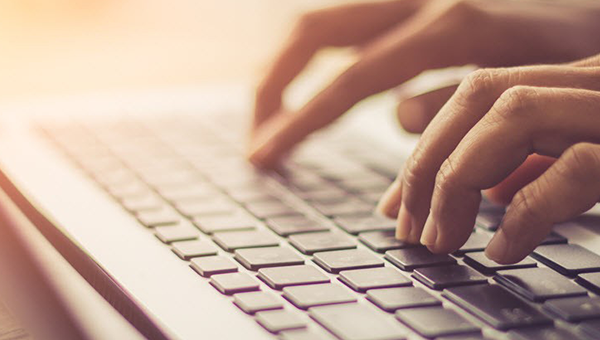 Hands typing on a laptop keyboard