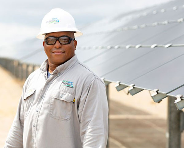 NextEra Energy Resources employee standing in front of a solar panel NextEra Energy Resources employee standing in front of a solar panel