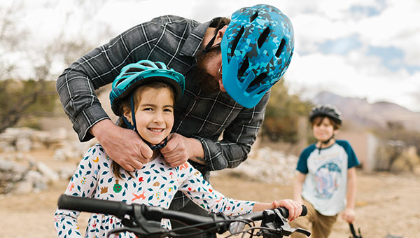 Father adjusting child's helmet on bike  