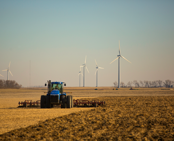 Wind turbines and a tractor in a dry open field Wind turbines and a tractor in a dry open field