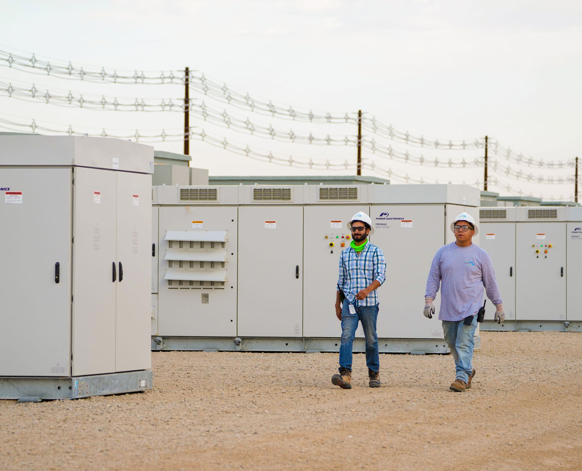 NextEra Energy Resources employees walking by battery energy storage untis. NextEra Energy Resources employees walking by battery energy storage untis.
