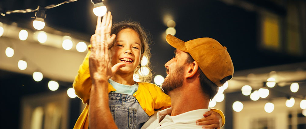 Father holding his daughter smiling under lights