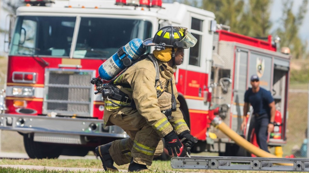 Firefighter in front of a fire engine grabbing a ladder