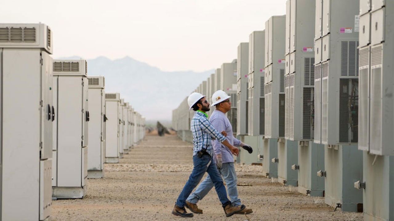 Two employees walking through battery energy storage units