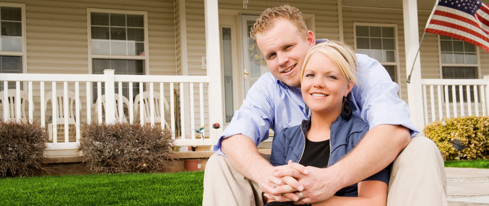 Couple sitting in front of their home