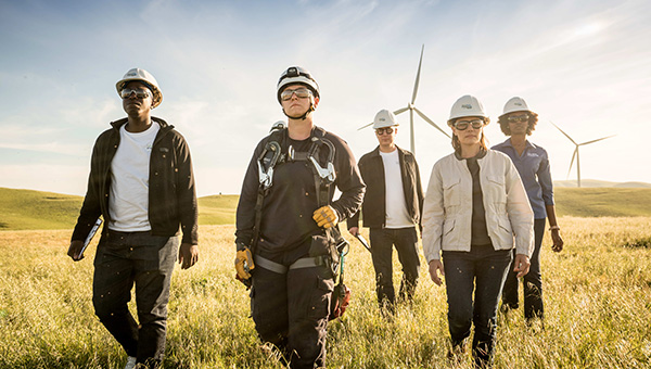 NextEra Energy wind turbine and solar energy construction employees walking in field.