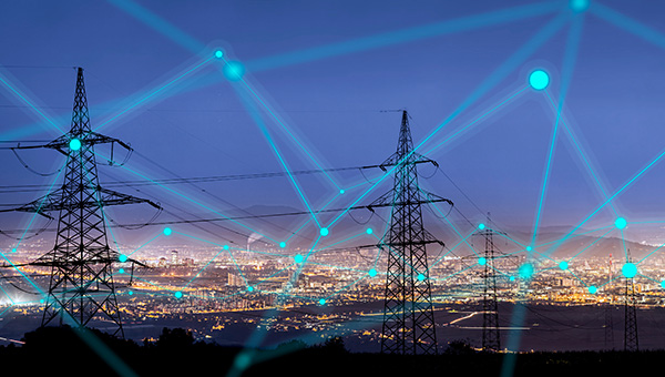 Overhead power lines and grid connection lines with city skyline in distance