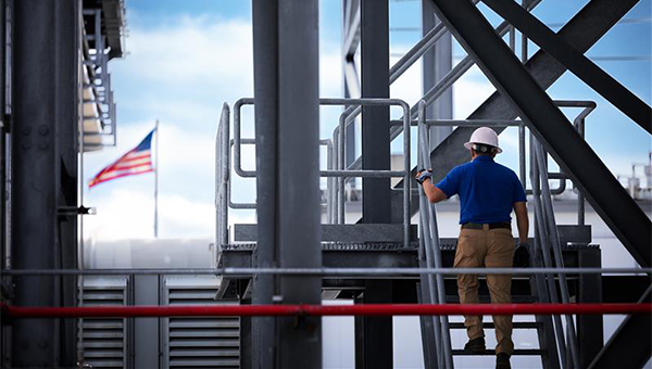 NextEra Energy Resources engineer on steps of an energy facility with American flag