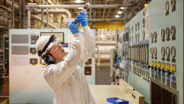 Seabrook Station technician checking sample in nuclear facility control room.