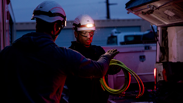 Two men with hard hats working outside at night