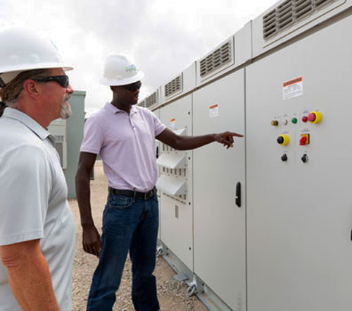 Two NextEra Energy Resources employees looking and pointing at an energy storage system unit.